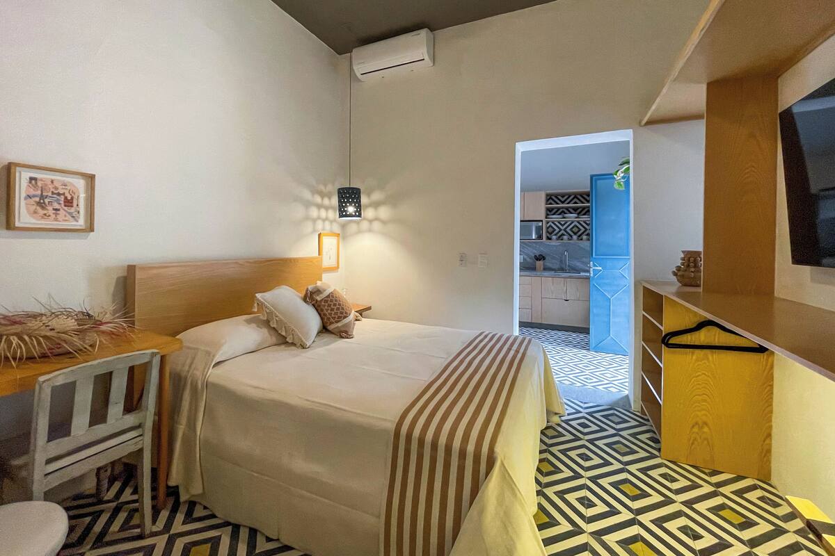 Een hotelkamer met een bed, een bureau en een stoel. In de achtergrond is een badkamer zichtbaar.