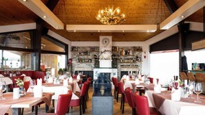 A restaurant with multiple dining tables, red chairs, a wooden ceiling, and a chandelier. - Holzchalet A-D by Interhome (Gerolstein)