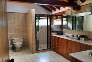 Ein Badezimmer mit Toilette, Dusche, Holzschränken und Waschbecken.