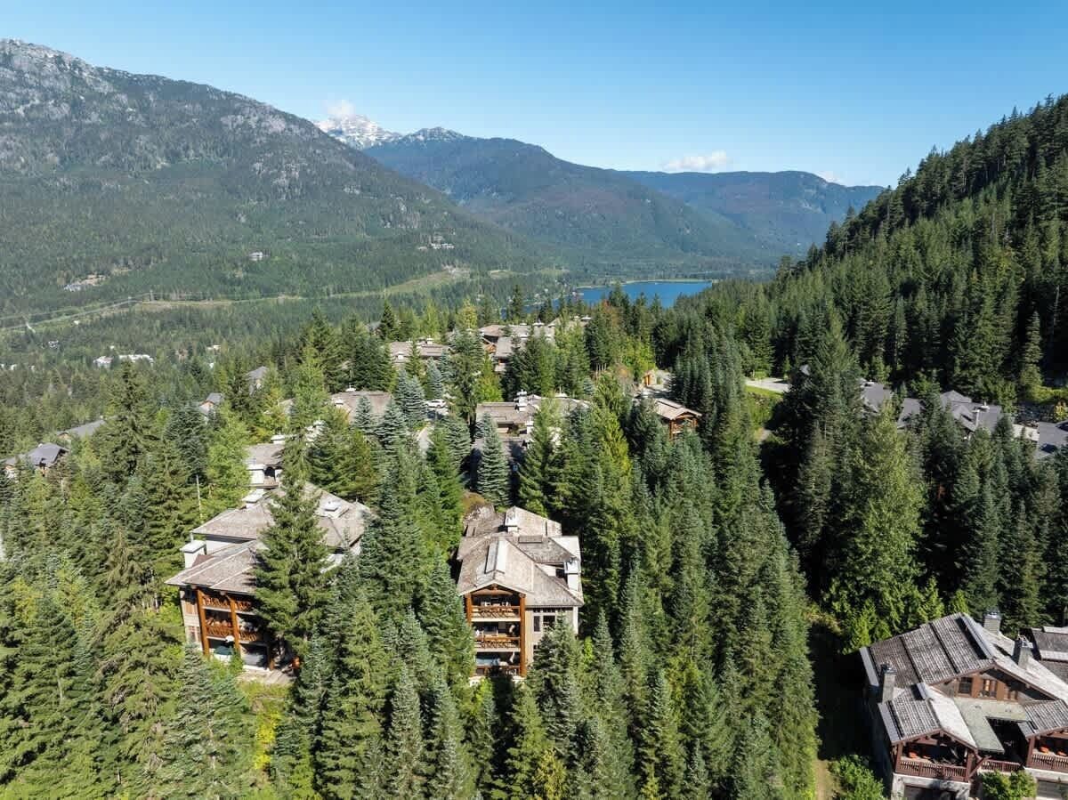 Un complexe hôtelier comprenant plusieurs bâtiments, entouré d’une forêt dense et de montagnes.