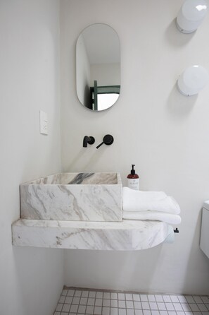 Un baño con lavamanos de mármol, un espejo y un perchero para toallas.