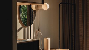 Ein modernes Zimmer mit Schreibtisch, Stühlen, einem runden Spiegel und einem Fenster mit Blick auf Grünflächen.