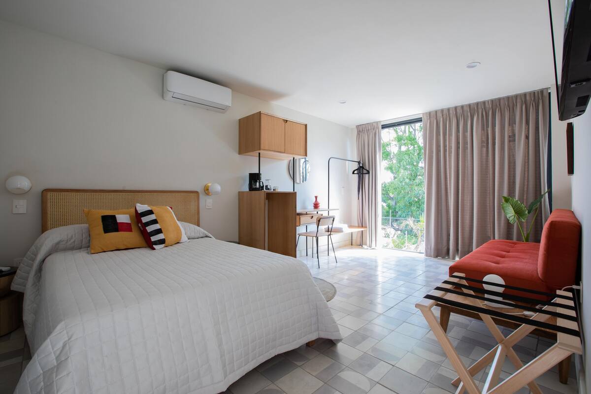 Una habitación de hotel con cama, escritorio, silla y televisión.