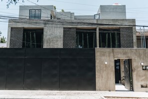 Un edificio moderno con una amplia fachada negra, una entrada visible y un cielo despejado.