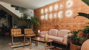 Ein modernes Wohnzimmer mit Backsteinwand, Ledersesseln, einer Couch und einem Couchtisch.