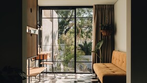 Ein modernes Wohnzimmer mit einer Couch, einem Essbereich mit Stühlen und einem großen Fenster mit Vorhängen.