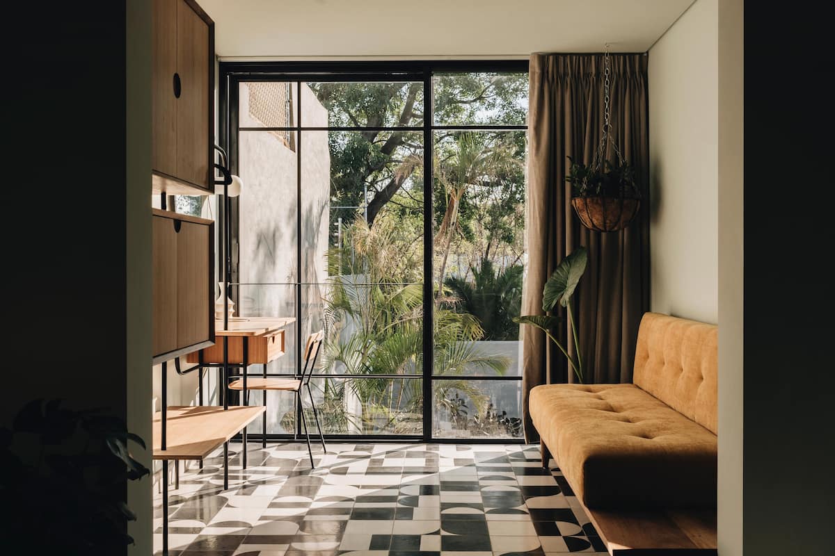 Una sala de estar moderna con un sofá, un comedor con sillas y un amplio ventanal con cortinas.