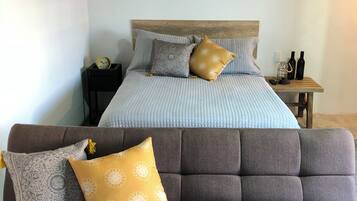A bedroom with a bed, a bedside table with two bottles, a clock, and a nightstand.