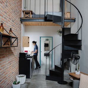 A modern kitchen with a brick wall, a wooden counter, and a black spiral staircase. - Casa Nican by Barrio Mexico (Guadalajara)