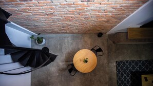 A room with a brick ceiling, a round wooden table with chairs, a potted plant, and a patterned wall.