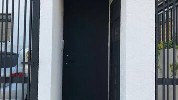 A black door with a number plate '1069' above it, leading to a tiled entrance area.