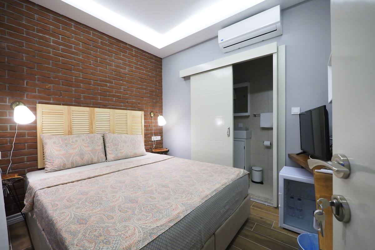 Une chambre à coucher comprenant un lit, une télévision, une armoire et un appareil de climatisation.