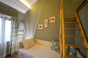 Ein Schlafzimmer mit einem Bett, einer Holzleiter und drei gerahmten Bildern an der Wand.