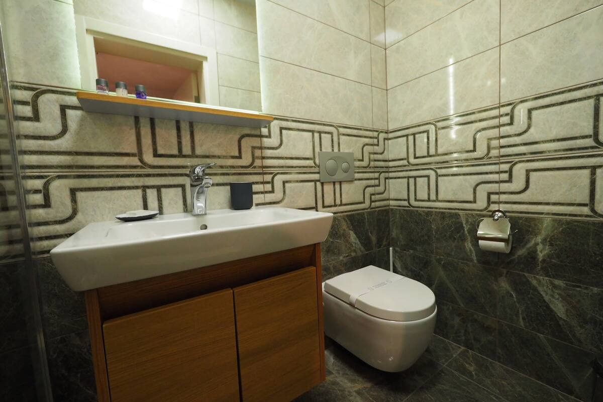Une salle de bain avec un lavabo, un miroir, des toilettes et des murs à motifs.