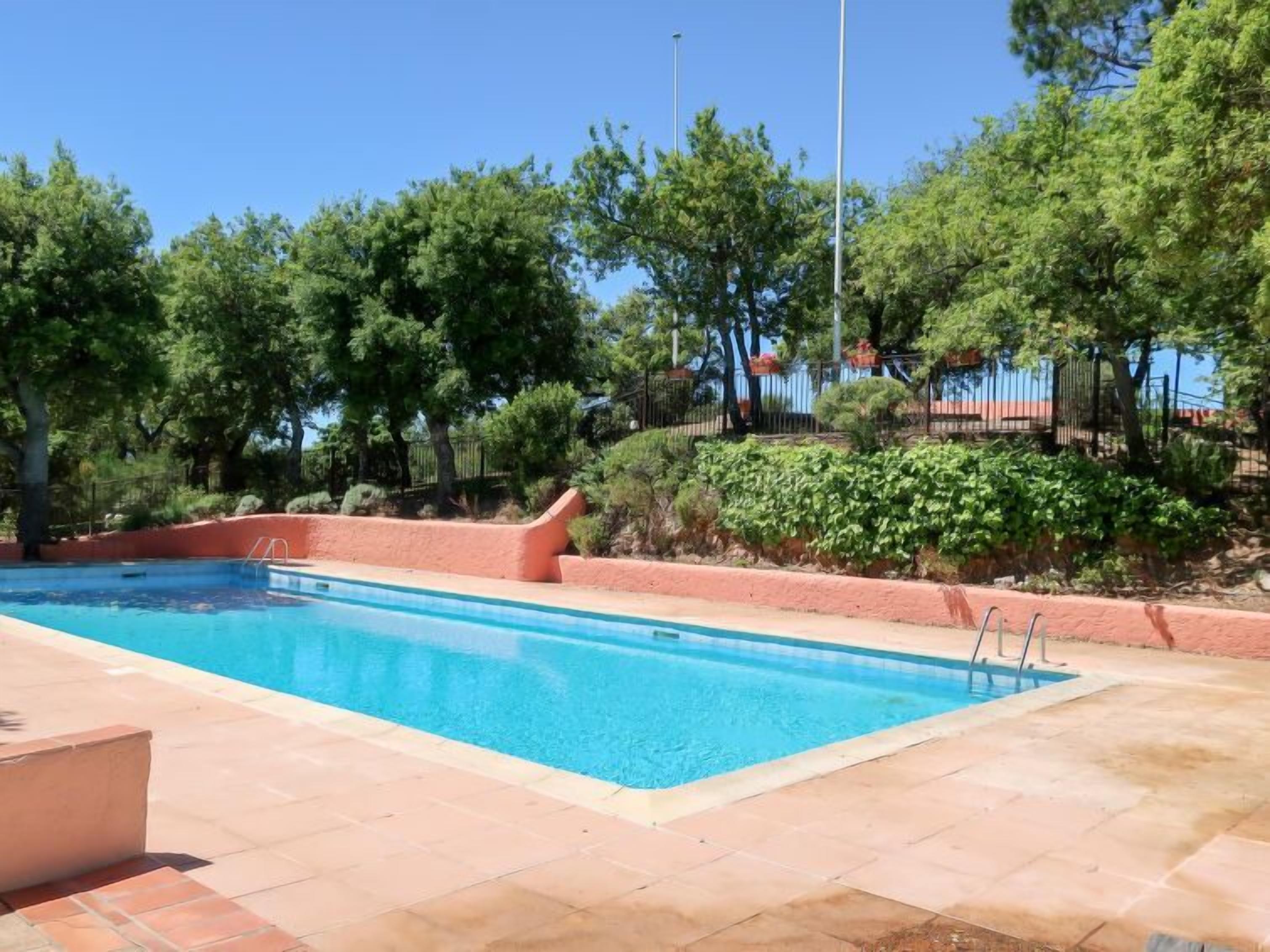 A rectangular swimming pool with clear blue water, surrounded by a tiled deck.