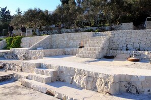 A stone amphitheater with tiered seating and a small stage. - Apartments Frano (Seget Vranjica)