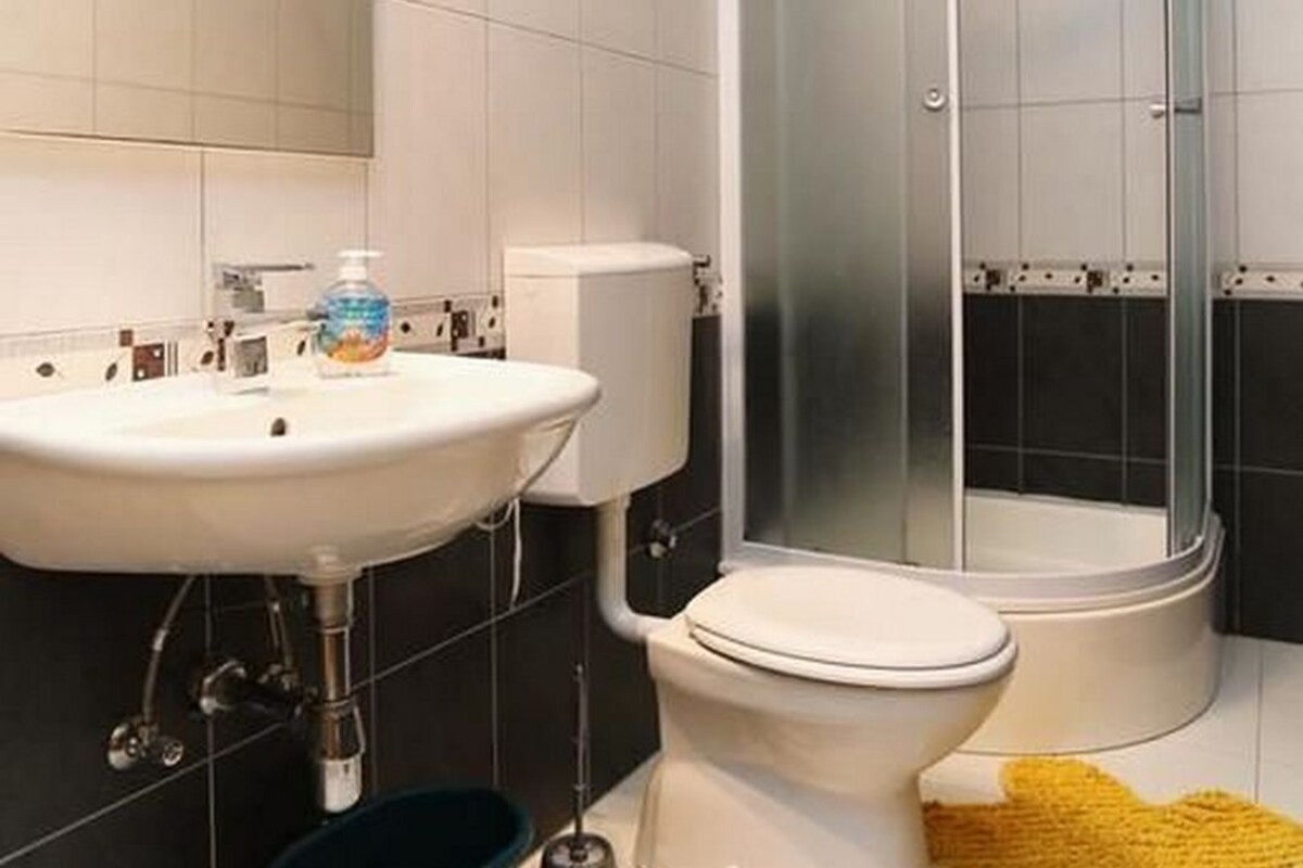 A modern bathroom with a white sink, toilet, and glass-enclosed shower.