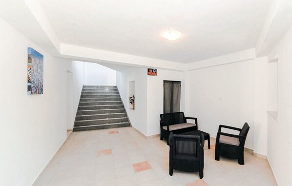 A hallway with a staircase leading to another floor, two black chairs, and a 'NO Smoking' sign.