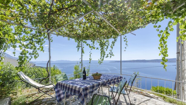 A table set up under a pergola with a view of the sea. - Apartment Boris (Brela)