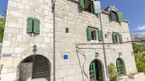 A stone building with green shutters, a sign reading "Radonica," and a staircase leading to an entrance. - Apartment Boris (Brela)