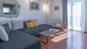 A modern living room with a grey sofa, a black and white chevron coffee table, and a stone wall feature. - House Villa Danica (Podstrana)