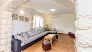 A modern living room with a stone archway, a sectional sofa, a wooden coffee table, and a small rug. - Apartment Luce (Vodice)