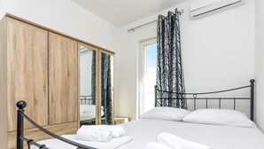 A bedroom with a bed, a wardrobe, a mirror, and a window with curtains. - Apartment Luce (Vodice)