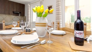 A dining table set with plates, cutlery, and a bottle of wine. - Apartment Luce (Vodice)