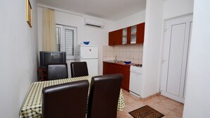 A compact kitchen with a dining area, including a table with chairs, a refrigerator, a stove, and cabinets. - Apartments Marijo (Sevid)