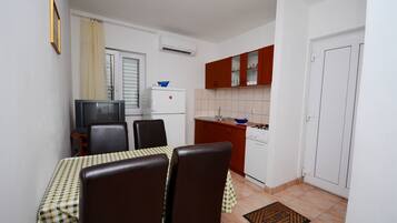 A compact kitchen with a dining area, including a table with chairs, a refrigerator, a stove, and cabinets.