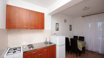 A compact kitchen with wooden cabinets, a white refrigerator, and a gas stove.