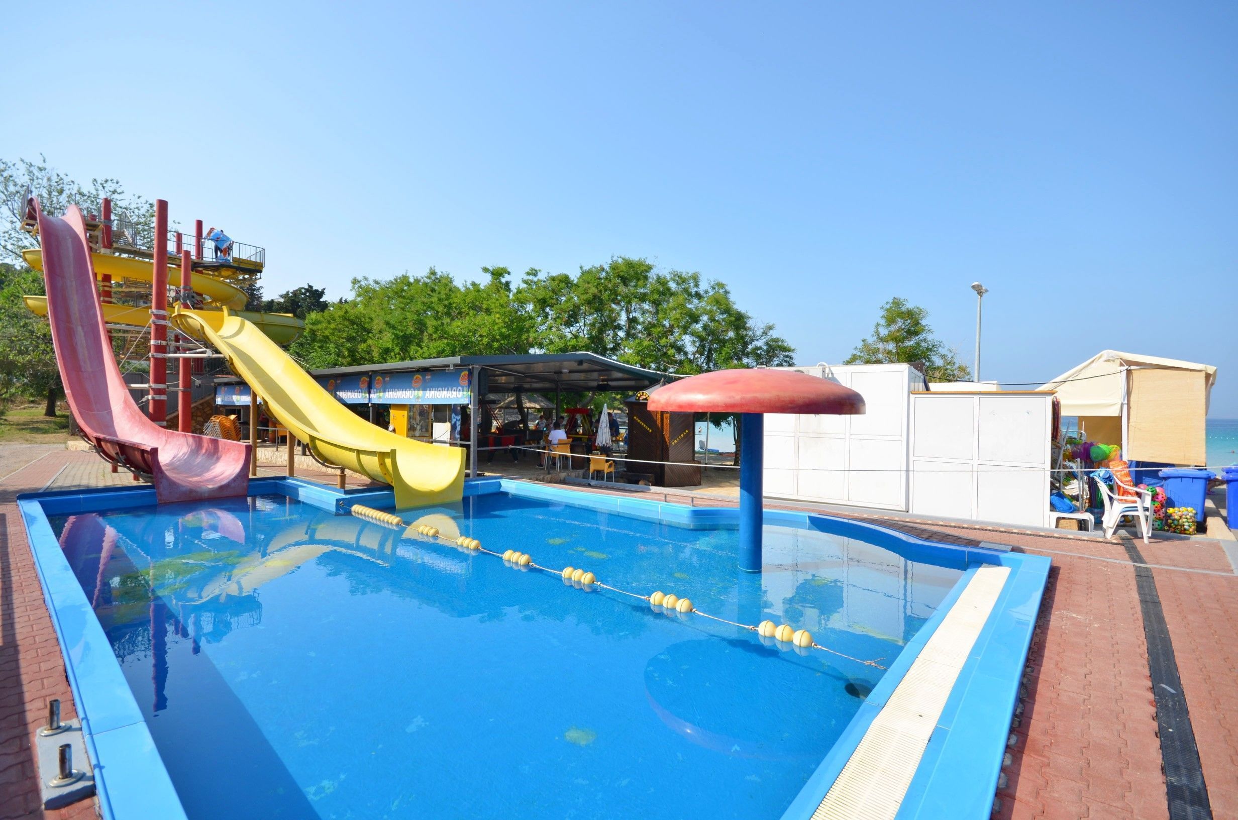 A swimming pool with slides and a covered seating area.
