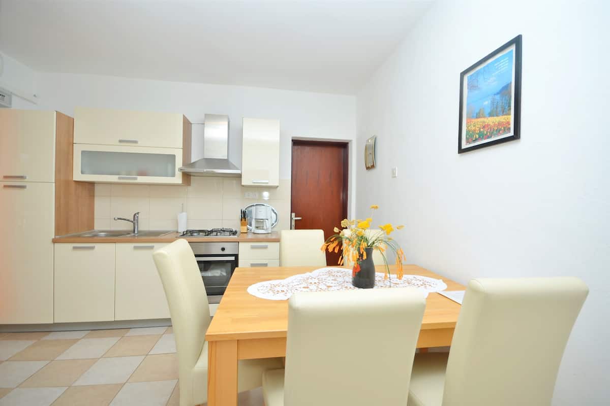 Una cocina compacta con comedor, que incluye una mesa de madera, sillas y un florero con flores.