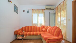 Egy hangulatos nappali, melyben egy nagy, csíkos mintájú kanapé, egy kis asztal és egy üveg kávézóasztal találhat ó.