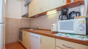 Egy praktikus, kis méretű konyha mosogatógéppel, kávéfőzővel és mikrohullámú sütővel felszerelve.