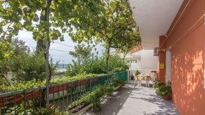 A covered outdoor area with a gravel path, green metal railing, and potted plants. - Apartments Ante (Igrane)