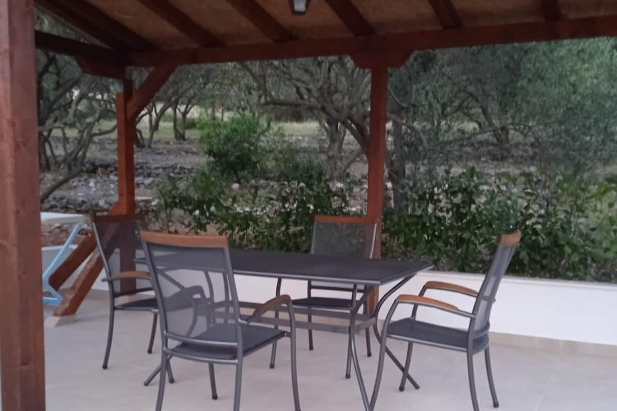 Ein überdachter Patio-Bereich mit einem runden Tisch und sechs Stühlen.