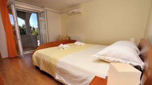 Une chambre d’hôtel comprenant un lit, une table de chevet, une lampe, une fenêtre et une porte coulissante donnant sur un balcon.