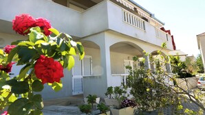 Un bâtiment à deux étages doté d’un balcon, de volets blancs et d’un mur en pierre.