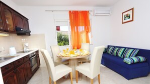 Une cuisine de taille réduite comprenant une table à manger, des chaises, un canapé et une fenêtre avec des rideaux.