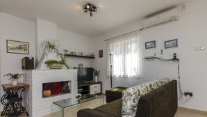 A living room with a fireplace, sofa, TV, and decorative items. - House Jadranka (Supetar)