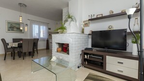 A living room with a fireplace, a dining area, and a TV. - House Jadranka (Supetar)