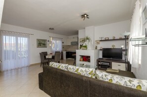 A living room with a sofa, TV, fireplace, dining area, and kitchen. - House Jadranka (Supetar)