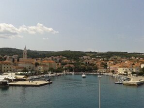 A coastal town with a marina, buildings with red-tiled roofs, and a church tower. - House Jadranka (Supetar)