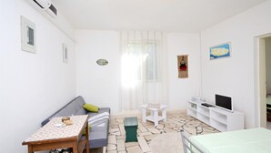 Un ambiente compatto con divano, un tavolino, televisione e un letto.