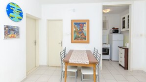 Un'area pranzo con tavolo e sedie, una cucina con elettrodomestici e due porte.