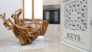 Eine Küche mit einem dekorativen Holzstück auf der Arbeitsplatte, einem weißen Schrank mit geschnitzten floralen Verzierungen und einem Fenster mit Tageslicht.
