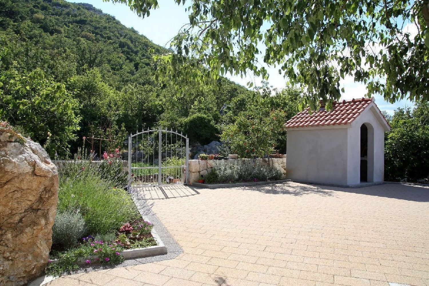 A paved courtyard with a small building and a metal gate.