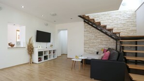 Ein modernes Wohnzimmer mit Treppe, Flachbildfernseher und Essbereich.