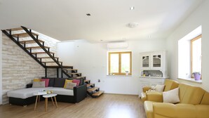 Ein großzügiger Wohnbereich mit Treppe, einer Couch, einem gelben Sessel und einem kleinen Tisch.